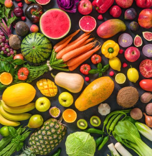 Colorful raw fruits and vegetables varied vegan food, vivid rainbow arrangement full frame background